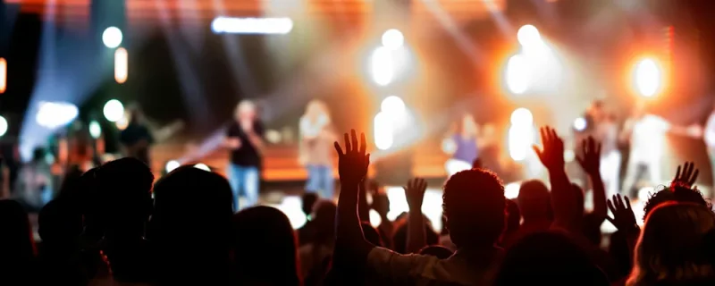 Popartister på scen under konsert med publik och scenljus