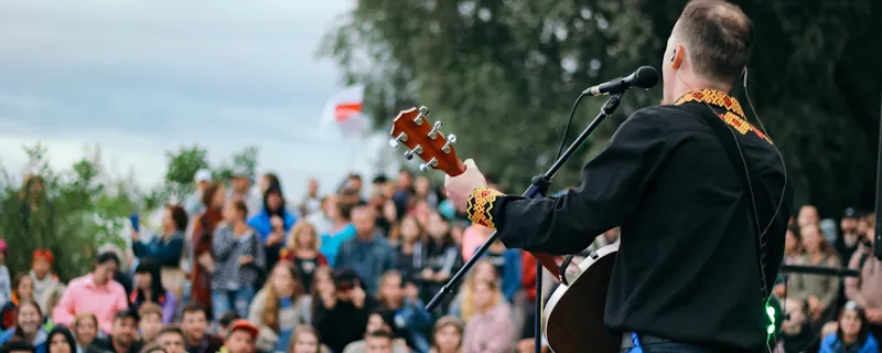 Folkartist spelar akustisk gitarr och sjunger live inför publik utomhus