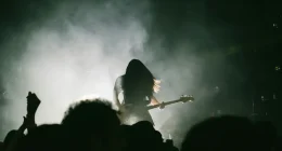 Siluett av metalmusiker med elbas på rökfylld scen inför publik under konsert