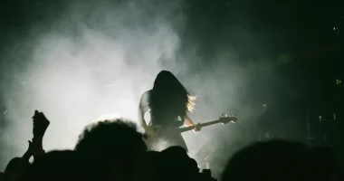 Siluett av metalmusiker med elbas på rökfylld scen inför publik under konsert