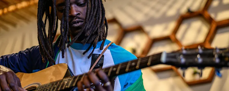 Reggaeartist spelar gitarr under framträdande i varm inomhusmiljö