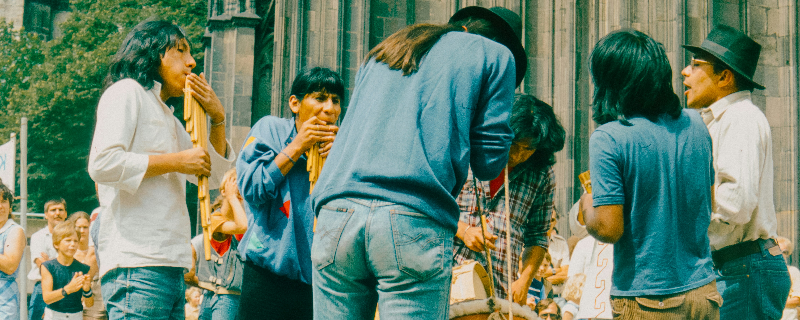 Världsmusiker spelar traditionella panflöjter under utomhusframträdande i stadsmiljö