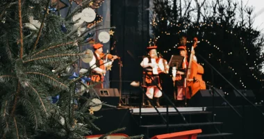 Musiker spelar på scen under en julkonsert i december med julgran och vinterdekorationer