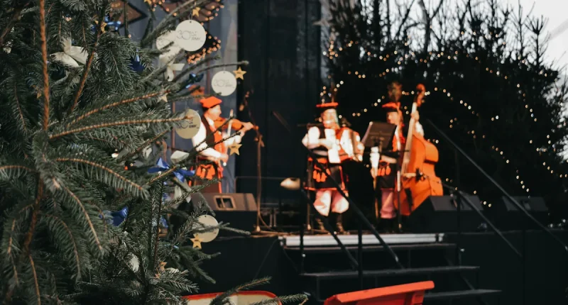 Musiker spelar på scen under en julkonsert i december med julgran och vinterdekorationer