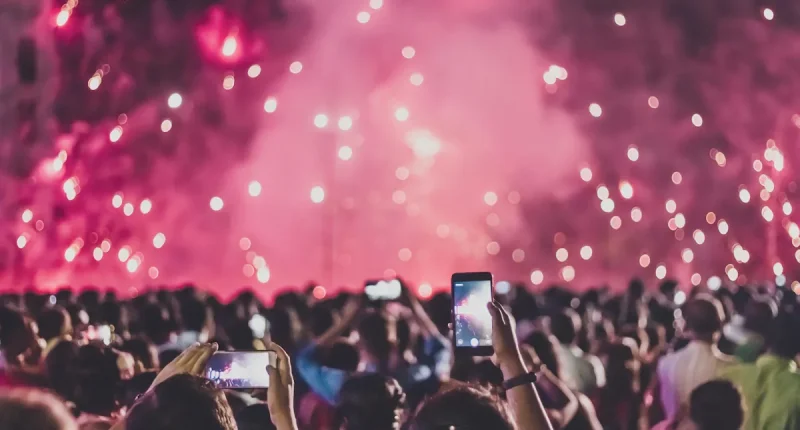 Publik filmar scenen med mobiltelefoner under en konsert i Stockholm med ljus och pyroteknik i bakgrunden