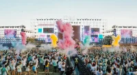 Stor publik framför scen under en färgsprakande utomhuskonsert i juni med rök, ljus och festivalstämning