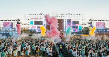 Stor publik framför scen under en färgsprakande utomhuskonsert i juni med rök, ljus och festivalstämning