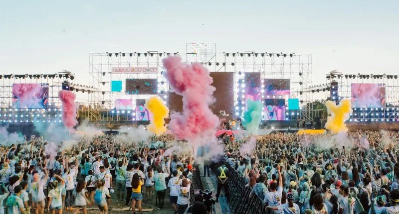 Stor publik framför scen under en färgsprakande utomhuskonsert i juni med rök, ljus och festivalstämning