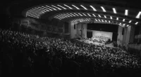 Publik i en fullsatt konserthall under en konsert i november med scen och kör på scenen