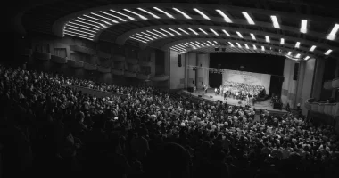Publik i en fullsatt konserthall under en konsert i november med scen och kör på scenen