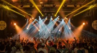 Publik framför scen under en energisk konsert i oktober med starka scenljus och händer i luften