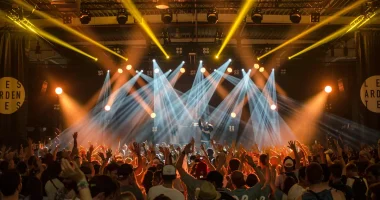 Publik framför scen under en energisk konsert i oktober med starka scenljus och händer i luften