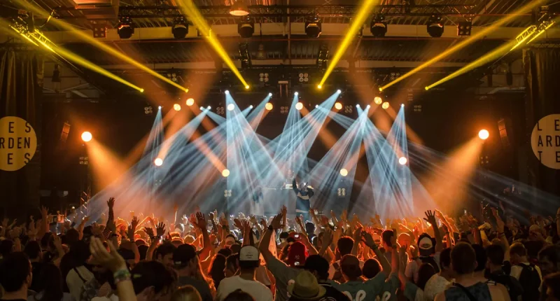 Publik framför scen under en energisk konsert i oktober med starka scenljus och händer i luften