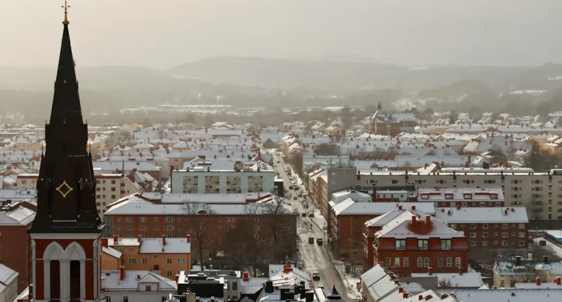 Snötäckt stadsbild i Umeå med kyrktorn och byggnader i centrala staden under vintertid